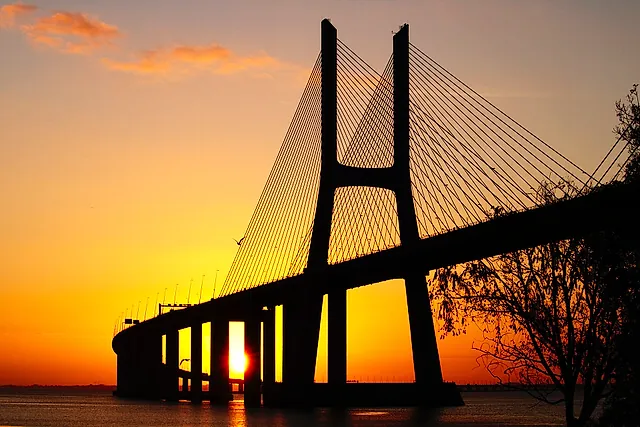 Il pilone del Ponte Vasco da Gama in controluce su un'alba arancione