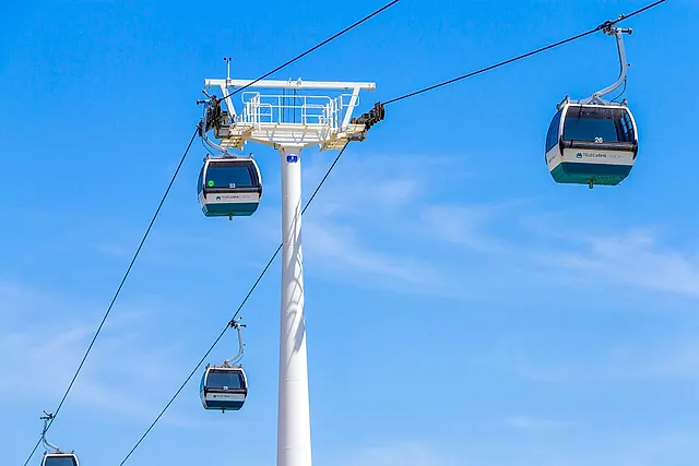 Cable car cabins passing a white pylon high above Parque das Nações in Lisbon